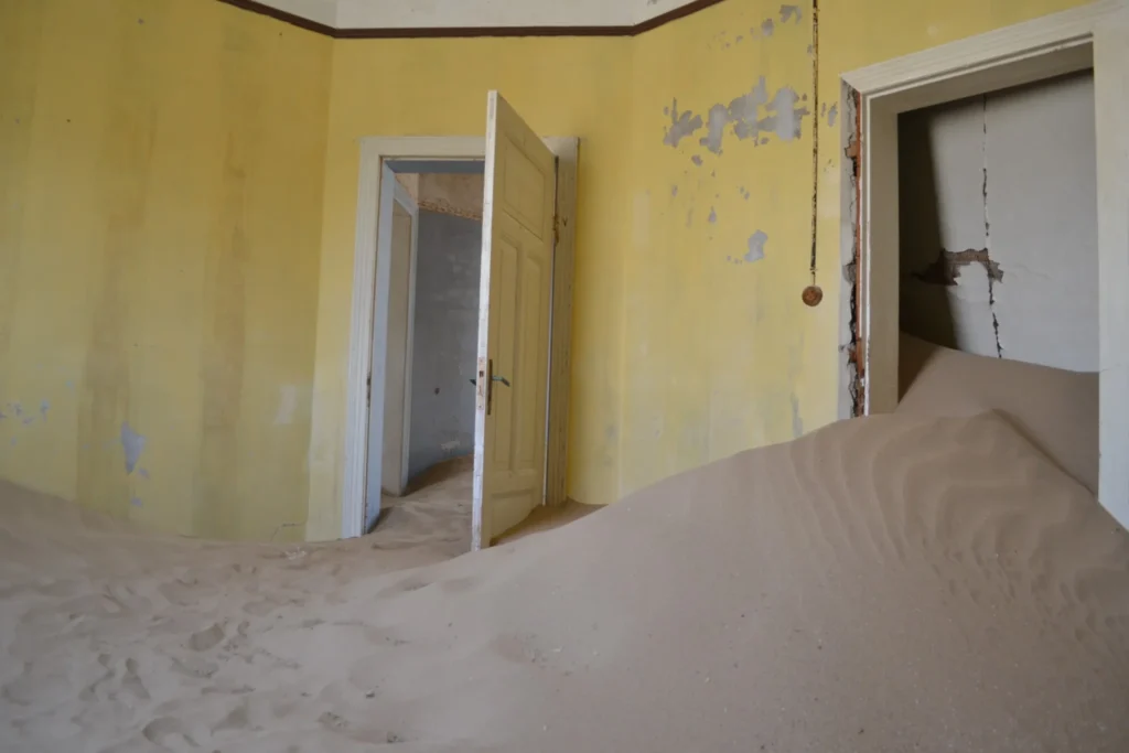 Yellow abandoned room at Kolmanskop filled with windblown Namib Desert sand